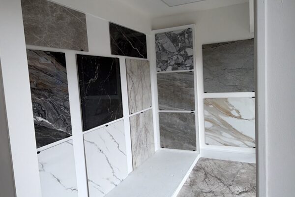 Tile showroom wall displaying marble sample tiles in a grid above a white bench.